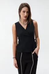Chaleco cruzado negro sin mangas con escote en V y lazo de ajuste lateral, confeccionado en tejido texturado.
