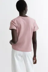 Remera de punto de algodón tupido color rosado, con cuello redondo ribeteado acanalado y mangas cortas.
