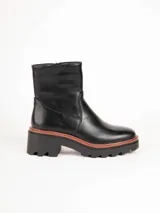 Bota baja de mujer color negro, con suela track gruesa y detalle de ribete marrón.