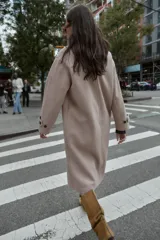 Abrigo largo de corte oversize con cuello de solapa, manga larga y cierre frontal cruzado con botones. Cuenta con bolsillos delanteros.