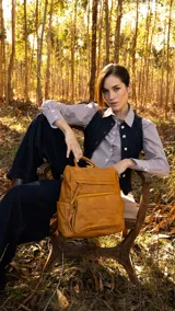 Mochila color mostaza de símil cuero, con apertura superior y dos bolsillos frontales con cierres metálicos. Incluye bolsillos laterales, tres bolsillos internos, correa larga regulable y correas para colgar en la espalda regulables.