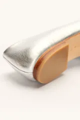 Chatas planas de cuero color plateado metálico, con punta cuadrada y un pequeño tacón bajo de madera.