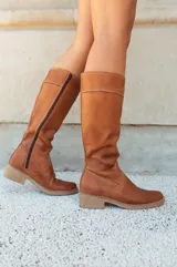 Bota de caña media alta color marrón, realizada en cuero engrasado, con cierre lateral y suela con vira.