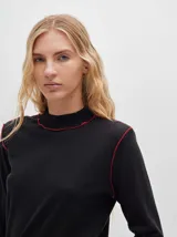 Polera de manga larga confeccionada en tela rib color bordó, con cuello alto y hombreras. Presenta costuras a la vista con pespuntes en hilo de color contrastante en el cuello, puños, hombros y ruedo.