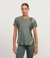 Remera deportiva de microfibra en color verde grisáceo, con cuello redondo, mangas cortas y detalle de estampa lateral con ondas en tonos contrastantes.