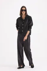 Pantalon de corte recto y holgado, confeccionado en material engomado de acabado satinado en color negro.