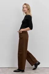 Pantalón de jean color marrón, de corte recto y tiro medio, con cierre de botón y cremallera, y bolsillos laterales.