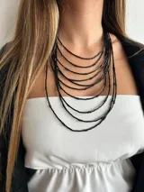 Collar de múltiples hilos negros con tubitos y cadena trasera para regular el largo.