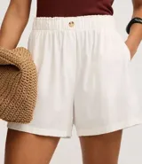 Short runner de viscolino, con cintura elástica, botón decorativo y bolsillos laterales. Presenta un corte evasé holgado con bajo redondeado.