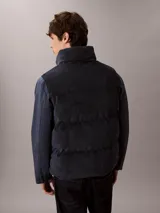 Chaleco acolchado reversible Calvin Klein, con diseño sin mangas, cuello alto y cierre frontal de cremallera. Presenta un lado de pana y otro de nailon liso.