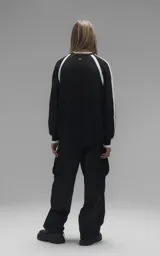 Sweater de punto negro con cuello redondo, mangas largas con franjas laterales blancas y puños en punto rib. Presenta un diseño gráfico bordado en el pecho con la inscripción 'RAVERS' y detalles en blanco.