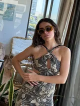 Vestido corto negro con estampado de plumas doradas, escote en V, breteles finos cruzados en la espalda, cut-outs laterales y volado en el ruedo.