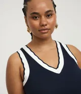 Top de punto acanalado color azul marino, corte ajustado, sin mangas y con cuello en V ribeteado en blanco.