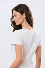 Remera blanca de manga corta y cuello redondo, con estampa frontal de una motoneta rosa estilo vintage con flores.