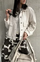 Sobrecamisa color crema con cuello camisero, cierre frontal con botones a presión, bolsillos de parche con solapa en el pecho y corte holgado.