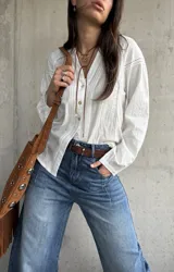 Camisa blanca de manga larga con detalles bordados en las mangas y encaje en el frente y hombros, escote en V con botones frontales.