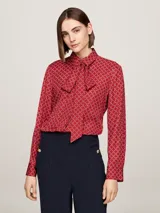 Blusa roja con estampado de rombos blancos, cuello con lazo y mangas largas con puños abotonados.