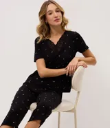 Pijama largo negro de viscolycra con estampa floral, compuesto por una remera de manga corta con escote en V y aplicación de encaje, y un pantalón con cintura elastizada.