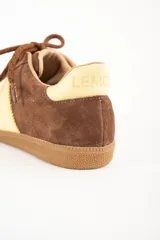 Zapatillas deportivas de gamuza color marrón con detalles en amarillo y suela de goma.