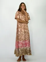 Vestido largo color marrón con estampado tie-dye en tonos rosados y blancos, con escote en V y mangas cortas. Presenta un volado en el ruedo.