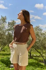 Short de gabardina beige de tiro alto, con bolsillos laterales y trabillas para cinturón. Incluye un cinto fino de cuero marrón con hebilla metálica dorada.