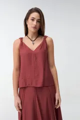 Musculosa bordó de tejido satinado, con escote en V y breteles con detalle de nudos en los hombros.