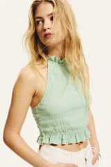 Top corto verde agua con textura arrugada, cuello halter con volantes y lazos para atar en la nuca, espalda descubierta y volantes en el ruedo.