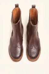 Bota tipo Chelsea de cuero vacuno color suela, con diseño brogue en la puntera y laterales. Presenta paneles elásticos laterales en color marrón oscuro, tirador trasero y suela de goma con plataforma.
