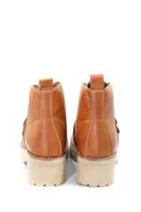 Borcego de cuero color beige con cordones, suela track de goma y detalle de hebilla metálica en el empeine.