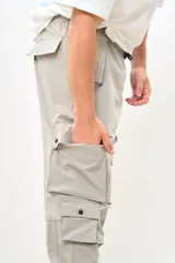 Pantalón cargo color gris claro, de corte amplio, con múltiples bolsillos con solapa y ajuste con cordón en la cintura.