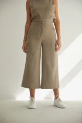 Pantalón palazzo color beige, de tiro alto, con bolsillos laterales y largo a la pantorrilla.