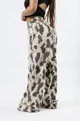 Pantalón wide leg con estampado de vaca en blanco y negro, de tiro alto y cierre de botón y cremallera.