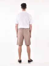 Bermuda color beige con cintura elástica y cordón ajustable, bolsillos laterales y corte por encima de la rodilla.