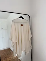 Ruana de tejido fino en color blanco, con diseño abierto y caída fluida, ideal para capas ligeras.