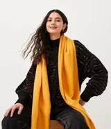 Chalina de poliéster color amarillo mostaza, de textura suave y terminaciones deshilachadas.