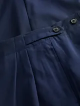 Pantalón sastrero de tiro medio color azul marino, con cierre de botón y cremallera, pierna ancha y largo completo. Confeccionado en tejido plano.