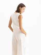 Top de denim blanco marfil, sin mangas, con escote redondo y costuras pespunteadas a la vista.