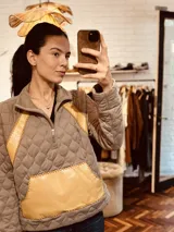 Sweater gris con diseño acolchado, cuello alto con cierre parcial y detalles en cuero amarillo bordado a mano en laterales y bolsillo frontal.