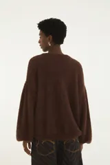 Sweater de tejido de punto con acabado afelpado, cuello redondo y mangas largas de volumen amplio. Diseño liso en color beige con silueta relajada.