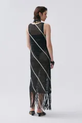 Vestido largo de punto calado negro con lurex y rayas diagonales blancas. Tiene escote redondo y flecos en el ruedo.