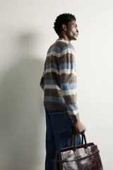 Sweater de punto con textura efecto pelo, cuello redondo, manga larga y diseño a rayas horizontales en tonos marrón, celeste y beige.