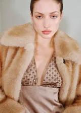 Vestido corto de fiesta confeccionado en tejido satinado con efecto arrugado. Presenta un diseño entallado sin mangas, con escote en pico, tirantes anchos y un detalle de adorno con lentejuelas y cuentas de cristal en la parte superior. Incluye forro interior y cierre de cremallera en la parte posterior.