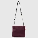 Cartera tipo bandolera de diseño minimalista, color bordó, con correa ajustable y desmontable. Presenta el logo de la marca grabado en el frente y una etiqueta lateral distintiva.