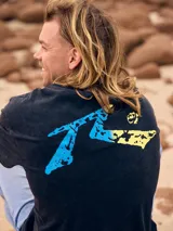 Remera negra de hombre con estampa azul y amarilla en la espalda.