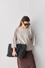 Sweater de punto liviano color beige melange, con escote bote y mangas amplias de largo tres cuartos que aportan una silueta relajada y fluida.