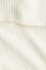 Top de punto acanalado con escote off-the-shoulder y mangas largas. Presenta un diseño ajustado con cuello vuelto y textura acanalada en toda la prenda.