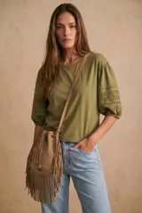 Remera de algodón color verde oliva, con mangas abullonadas de largo 3/4 que presentan detalles de bordado inglés calado. Posee cuello redondo y un corte holgado.