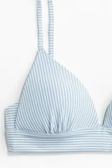 Top de bikini con estampado a rayas azules y blancas, breteles ajustables y copas con relleno push-up. Cierre de gancho en la espalda.