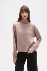 Buzo de manga larga color negro, con cuello alto tipo mock neck y corte holgado. Presenta costuras tipo raglán en los hombros.