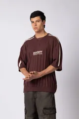 Remera de tejido de punto con textura calada, color crema con rayas verticales sutiles. Presenta cuello en V, mangas cortas con franjas laterales en color marrón oscuro y logo bordado en el centro del pecho.